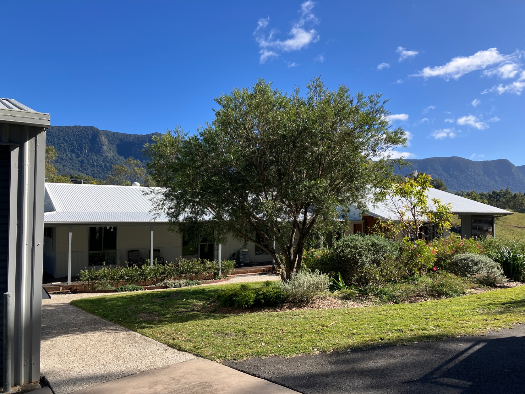 A homestead nestled at the foot of the mountains, framed by gardens and trees