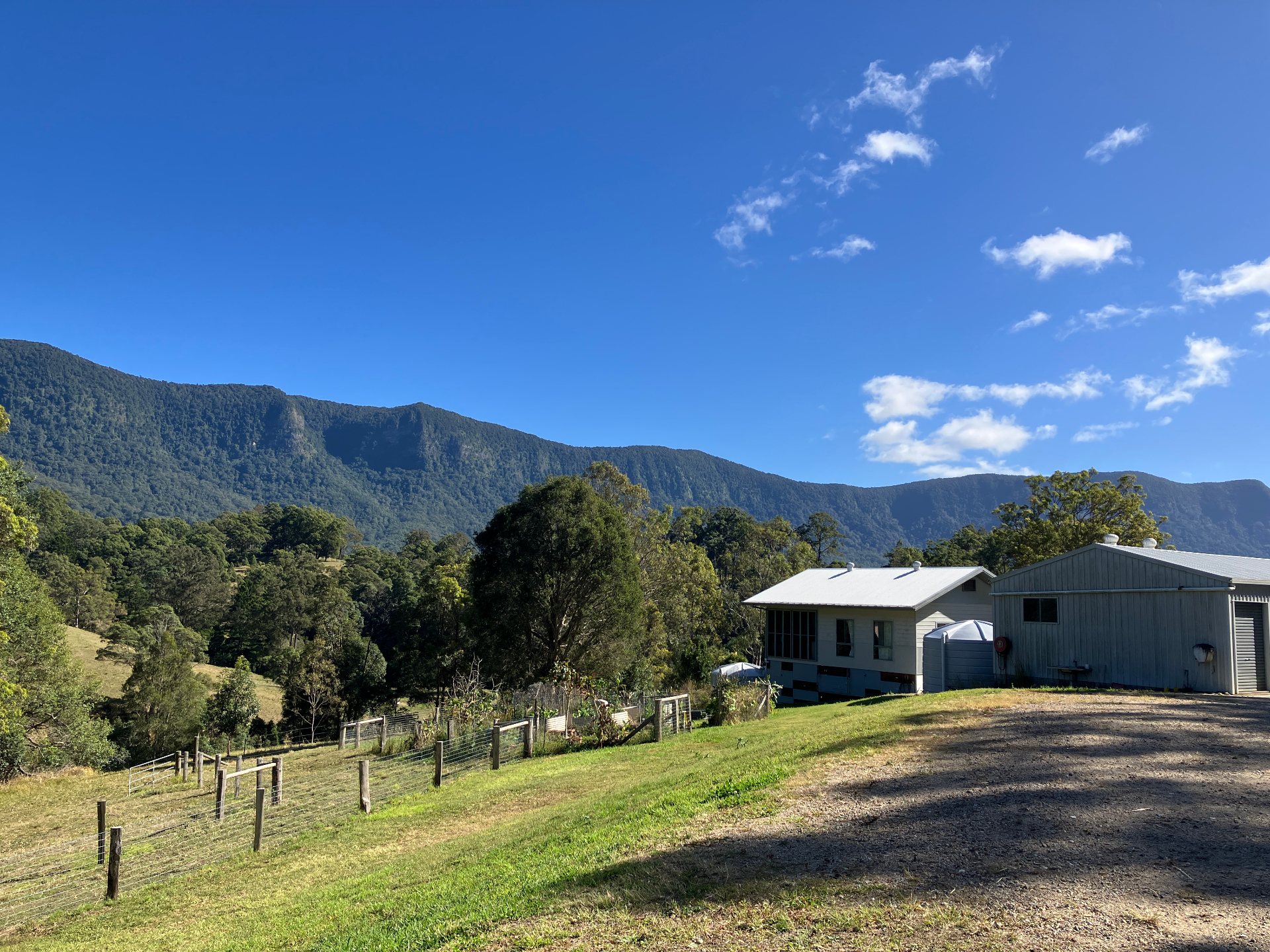Mountain ranges of the Northern Rivers rising behind a property and shed